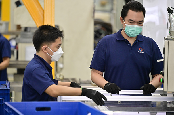 Two male workers at a battery manufacturing plant.