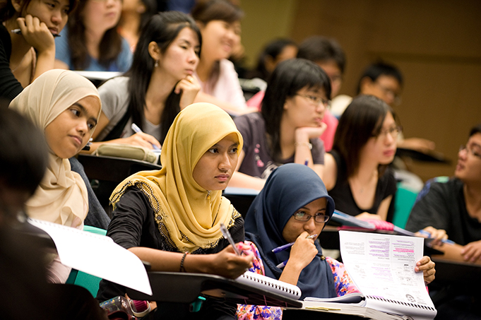 University students taking notes in a lecture room.
