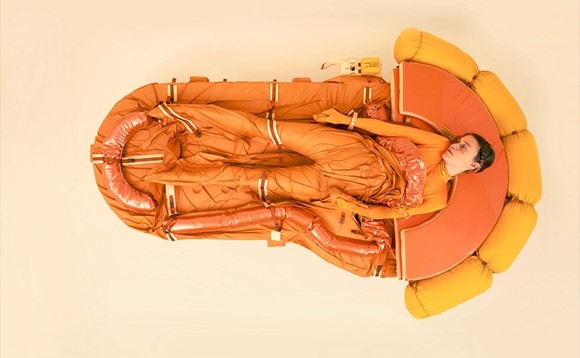 Woman clothed in orange, lying on her back in an orange sleeping bag
