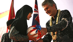 Photo of Mr Smith handing a soccer ball to a female school student