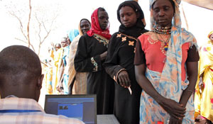 Women wait in line to be verified by a biometric registration system before receiving preventative nutrition products.