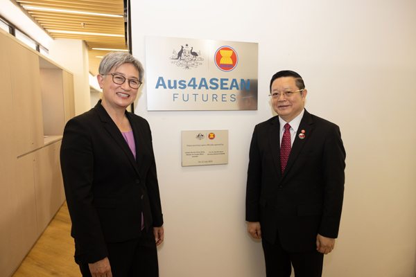 Two officials stand beside an Aus4ASEAN Futures plaque at an education and partnership facility.
