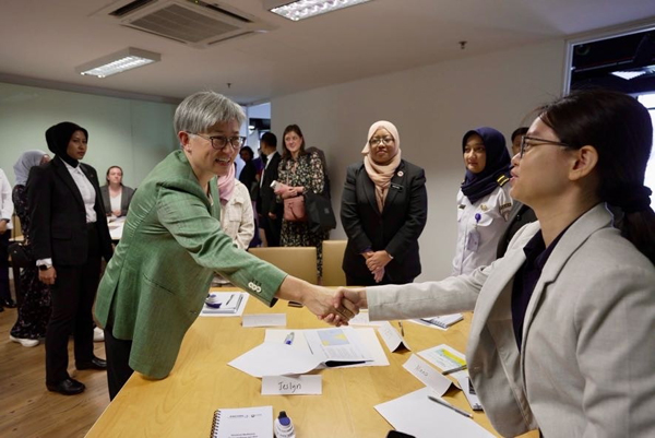 Participant greets attendees across a table during a regional partnership and leadership workshop.