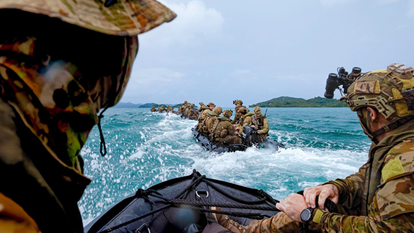 Military personnel travel by inflatable boat during a maritime exercise.