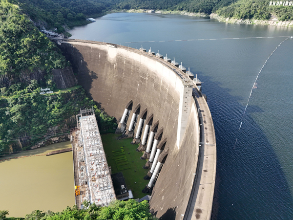 Aerial view of a hydroelectric dam and reservoir surrounded by forest.
