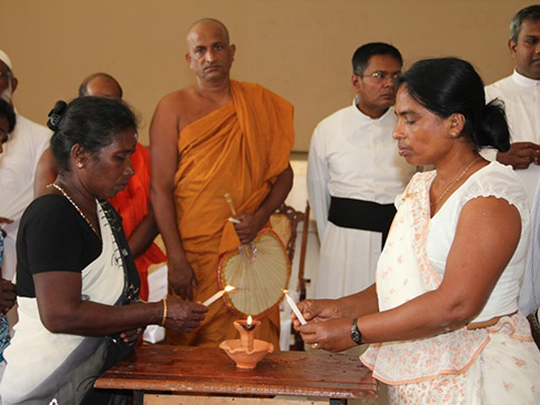 People watching two women lighting an incense burner