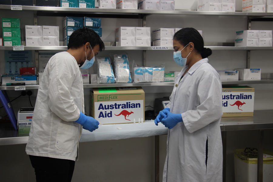Photo of two laboratory technicians using Australian-provided cartridges to test for COVID-19.