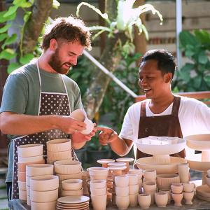 Two people standing behind a pottery display