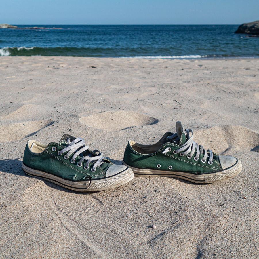 A photo of pair of green sneakers on the beach. 