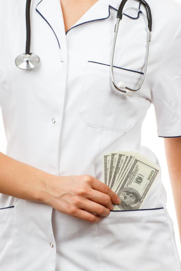 A photo of a nurse in uniform putting money in her pocket. 