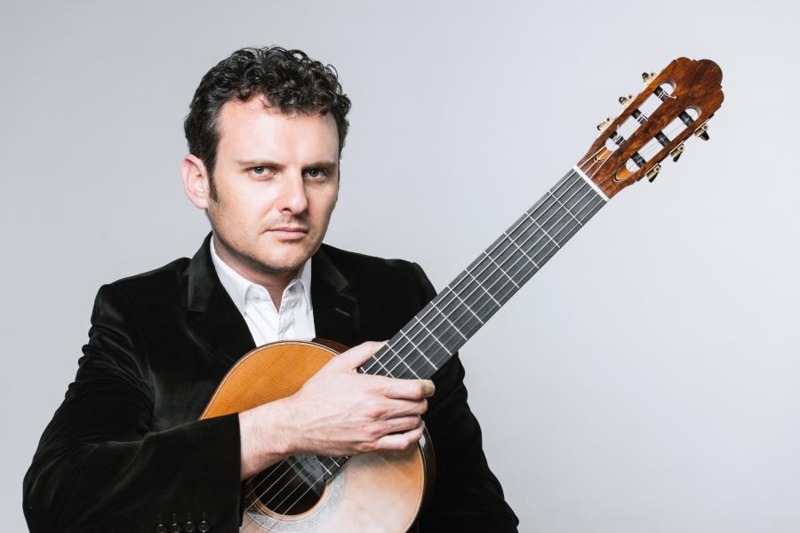 A photo of the musician holding his guitar. 