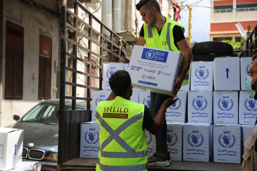 Two men in fluoro vests work together to unload World Food Programme supplies from a truck in Beirut.