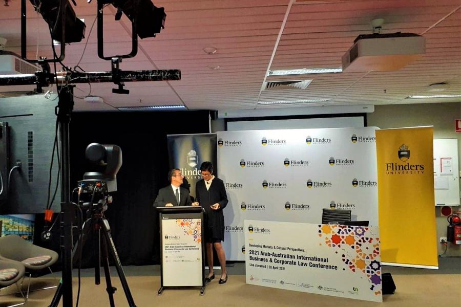 Speakers at a podium with cameras on tripods directed towards them