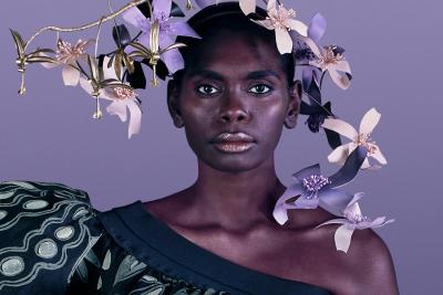 Indigenous model in dress with puffed sleeve on right shoulder and floral headdress