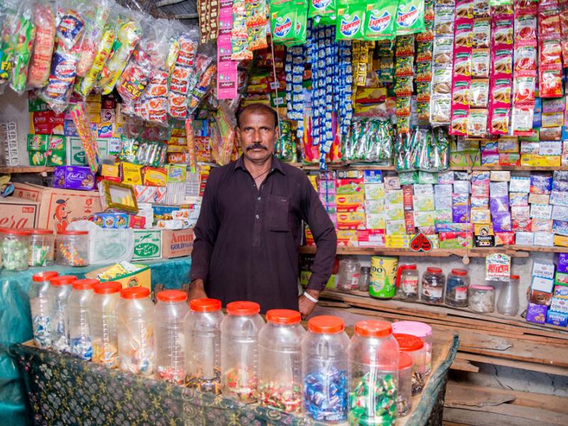 Photo of Anwar selling multiple products in an open street side store. 