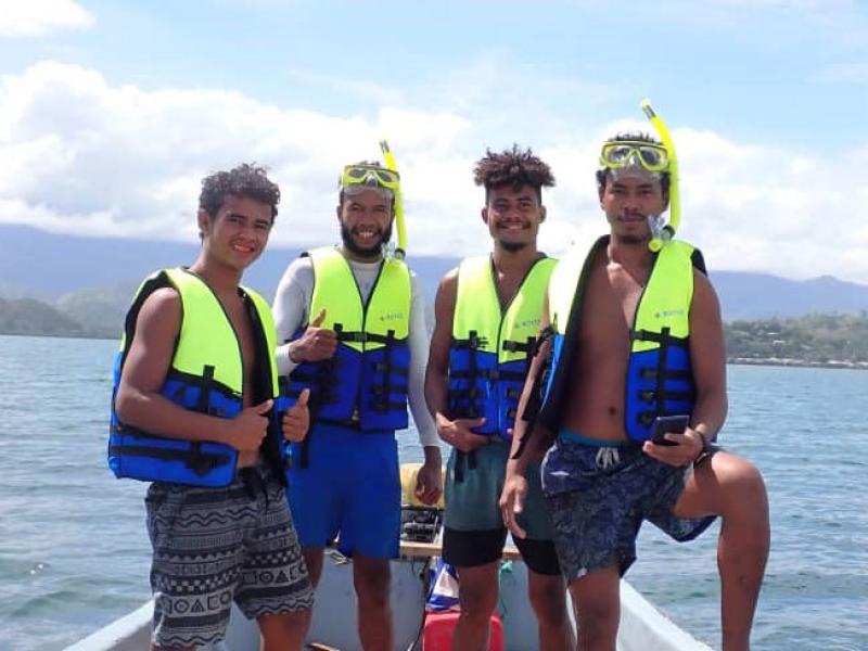 Group photo of 4 PNG boy in a tinnie boat off the coast.