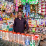 Photo of Anwar selling multiple products in an open street side store. 