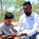 Photo of Dutjahn Custodian giving the Western Australia, Dutjahn Sandalwood Oil to a little boy.