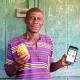 Photo of a person holding a piece of fruit and a phone with the AgUnity app open.
