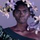 Indigenous model in dress with puffed sleeve on right shoulder and floral headdress