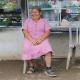 Female with a prosthetic leg, smiling and sitting on a chair in front of a food stall