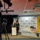 Speakers at a podium with cameras on tripods directed towards them