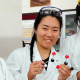 Jasmine in a white coat, goggles on head and holding helixes. 