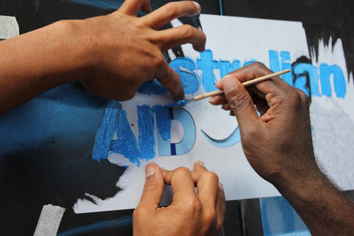 Two people painting an Australian Aid themed painting