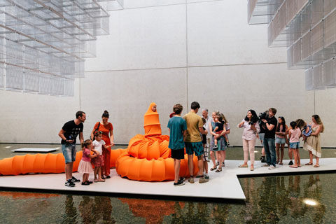 tourists looking at women dressed in art on a small walk way surrounded by water