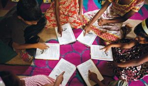 A group of children sitting in a circle writing