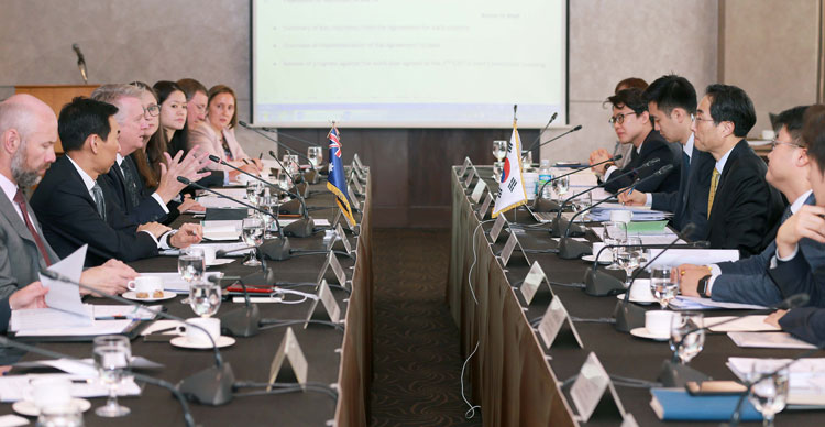 Korean delegates on one side of a meeting table and Australian delegates on the other side.
