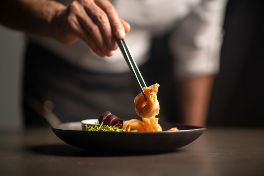 Decorative image of person embellishing the food on a plate.