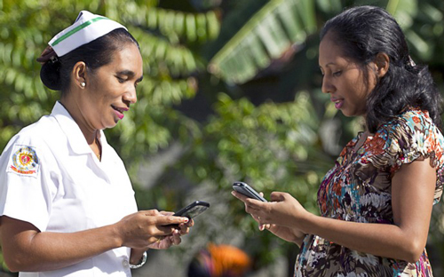 A midwife and a pregnant woman holding mobile phones