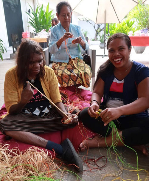 Women smiling and weaving together.