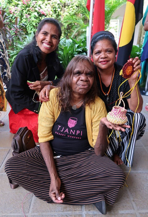 Master weaver Rene Kulitja posing for photo with two women.
