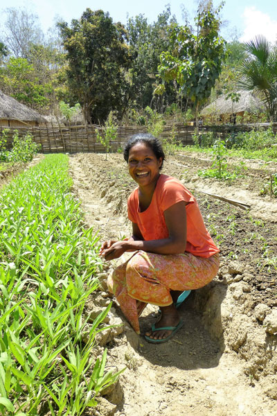 Woman kneeling next to row of plants