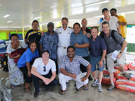 People posing for a photo in a storage shed containing supplies.