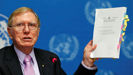 Michael Kirby holding up a copy of the report
